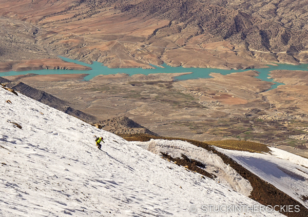 Chris Davenport skis Jbel Ayyachi, with the vast desert background and local reservoir inthe distance.