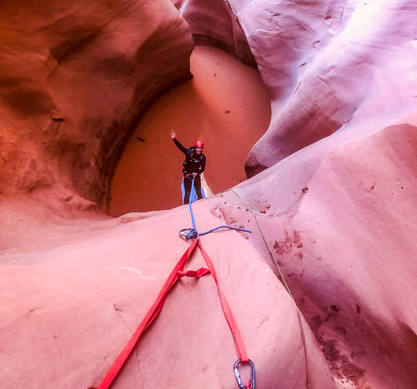Ted Mahon rappelling into a pool of water in a slot canyon